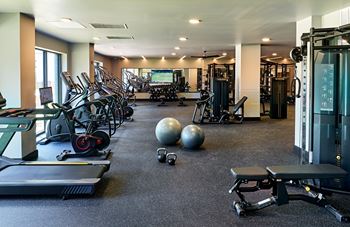 A gym with weights and other exercise equipment and a tv on the wall
